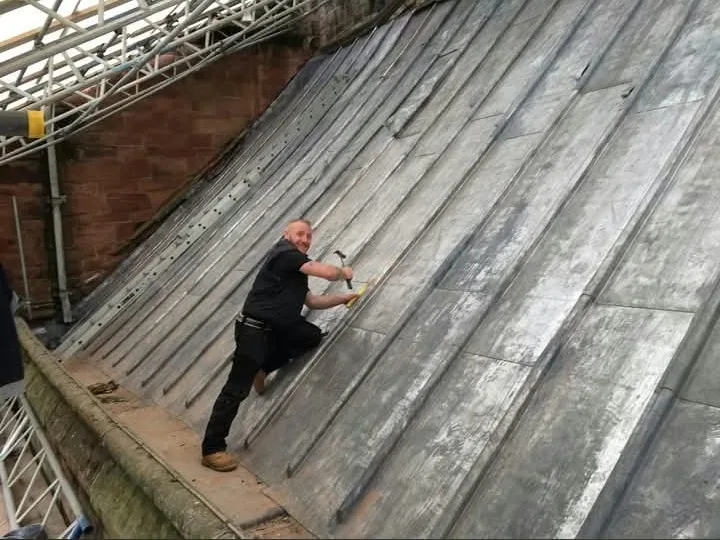 Stuart working on a lead-covered pitched roof beneath scaffolding