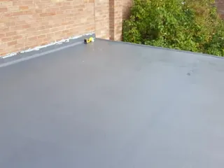 Finished flat roof beside a brick wall