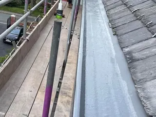 Long GRP fibreglass gutter installed alongside a slate roof